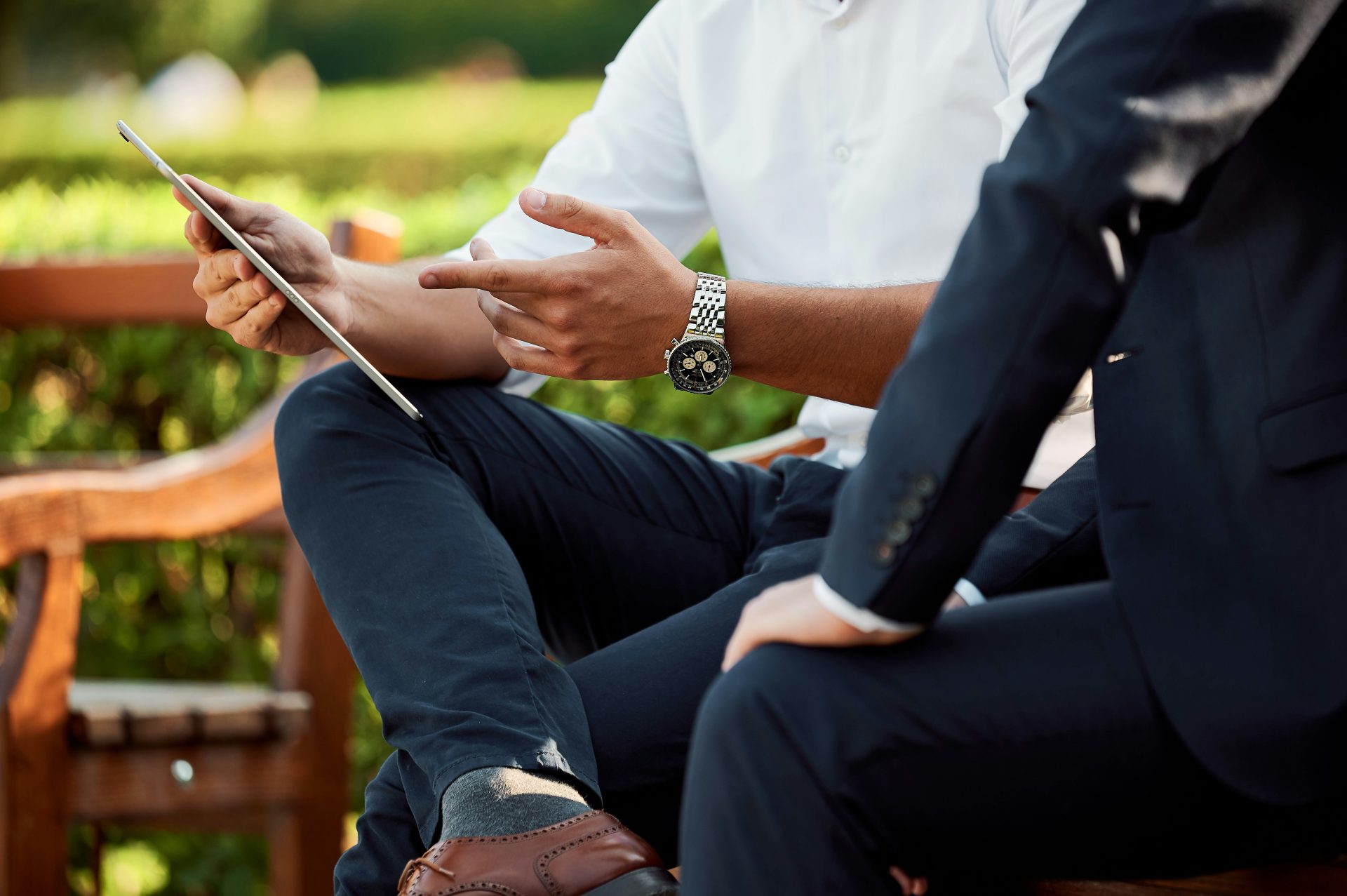 Businessmen discussing project using digital tablet outdoors.