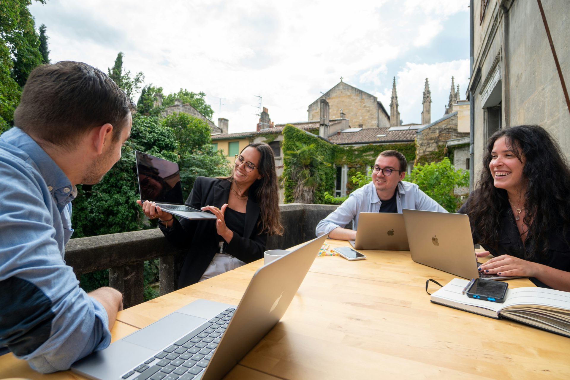 Outdoor business meeting with laptops and notes.