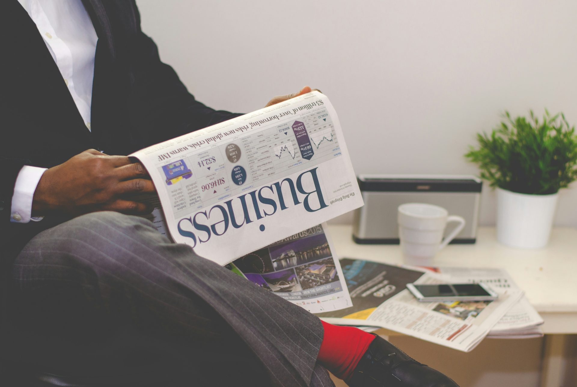 Man reading business newspaper with coffee nearby